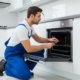 Professional technician repairing a built in gas cooker oven in a modern UAE kitchen.