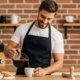 A smiling barista pouring coffee from a glass pot next to a modern espresso machine in a cozy café setup.