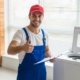 Smiling technician in blue uniform giving thumbs up after completing a washing machine repair in Dubai, UAE.