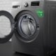 Front-load washing machine with clothes inside, placed between laundry baskets in a modern home laundry area.